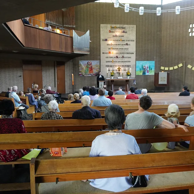die Vaterunserkirche von hinten gesehen, 20 Menschen sitzen in den Bänken