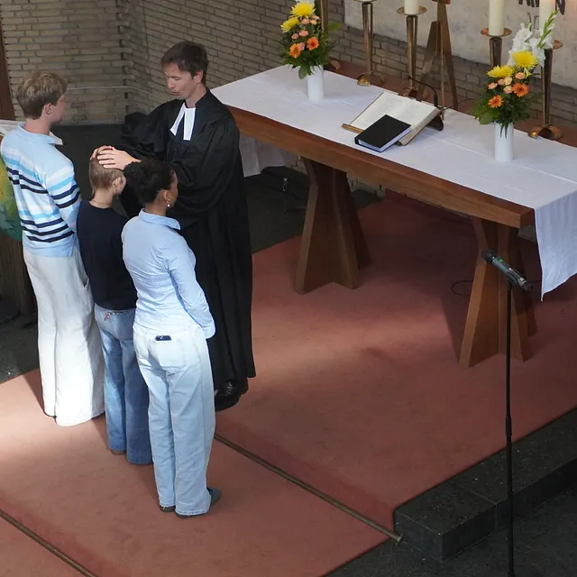 Drei Menschen und der Pfarrer stehen vor dem Altar.
