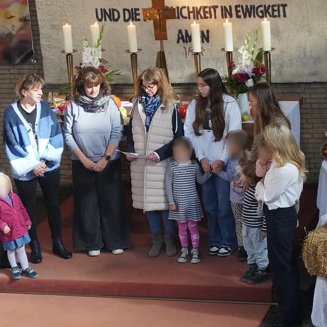 Erwachsene und Kinder stehen vor dem Altar und blicken zur Gemeinde.